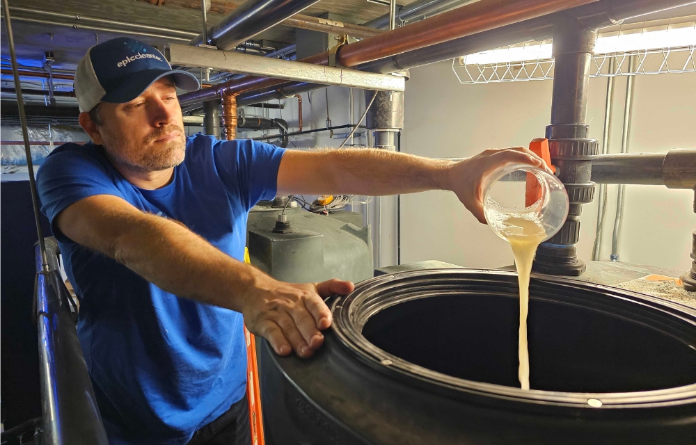 Certified Epic Cleantec operator Ryan T pouring chemicals into an onsite water reuse system
